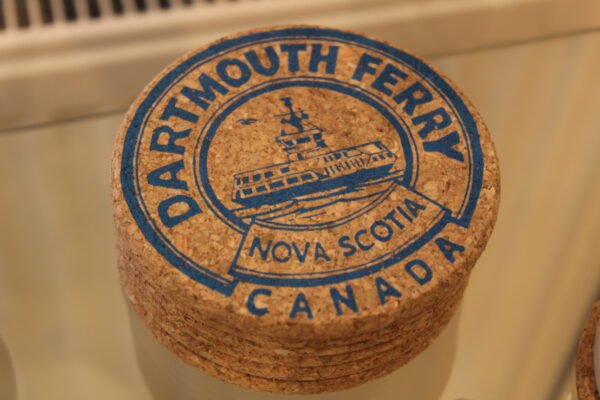 a cork coaster with blue screen print image of a ferry boat with the text Dartmouth Ferry Nova Scotia Canada